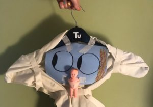 A mobile created by a participant as part of a Republic of Learning workshop, with a face, a baby and materical attached to a coat hanger