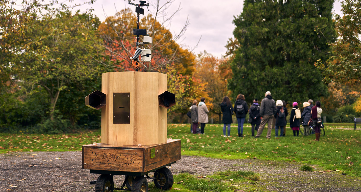 Future Machine in the memorial gardens in Finsbury Park with the procession in the background and trees behind