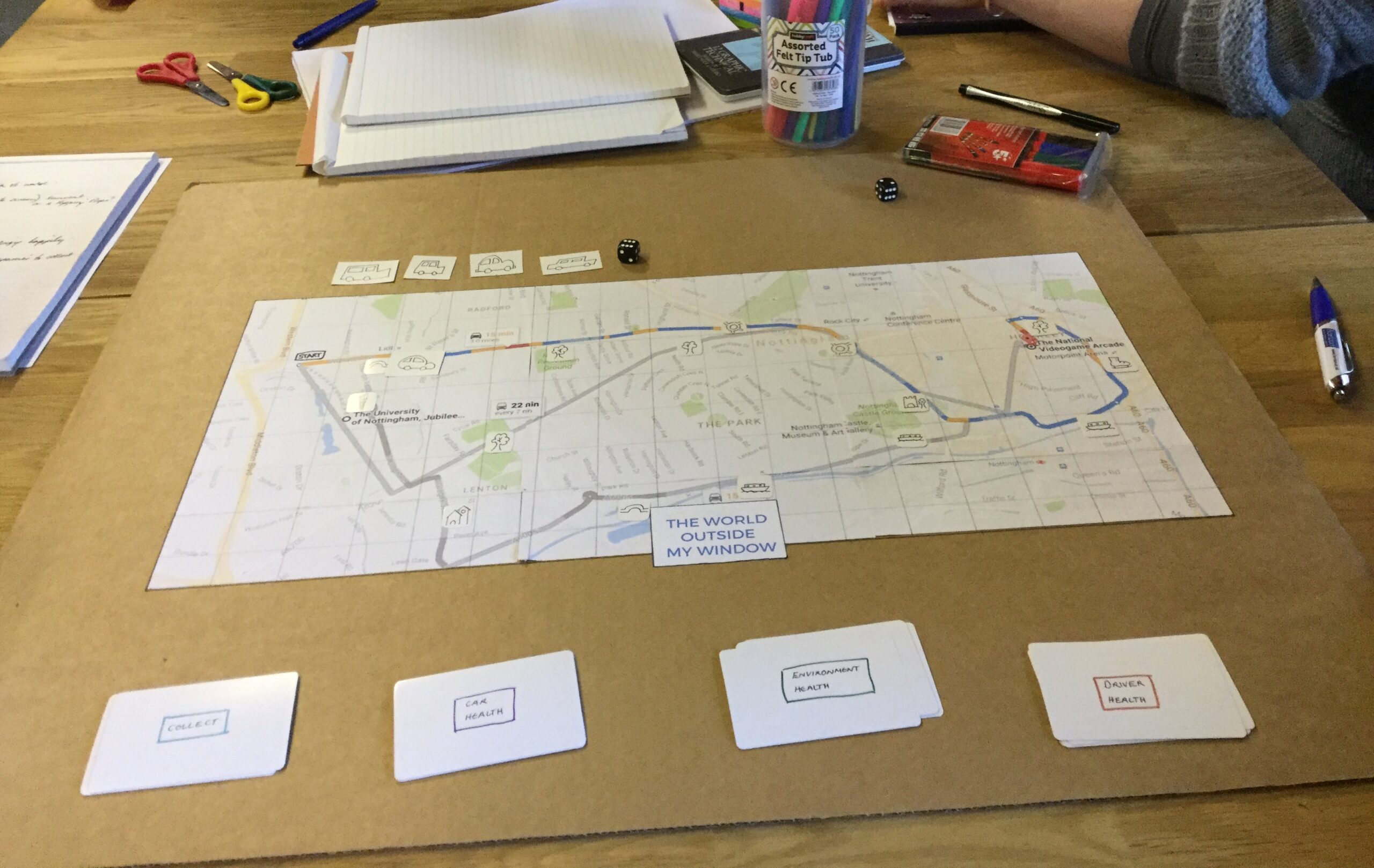 A paper board game - entitle 'the world outside my window' with a board and 4 sets of large cards, 4 sets of small cards and a dice