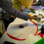People sitting around the table making an artwork from brightly coloured felt, with plates for biscuits, scissors and glue on the table.