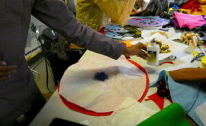 People sitting around the table making an artwork from brightly coloured felt, with plates for biscuits, scissors and glue on the table.