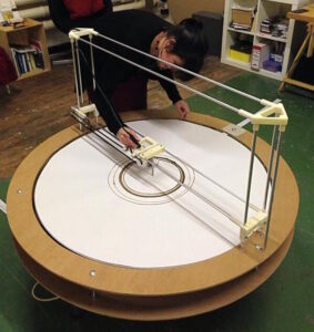 Rachel Jacobs with her artwork the Climate Machine, a circular device with a soldering iron that burns circular CO2 data onto paper