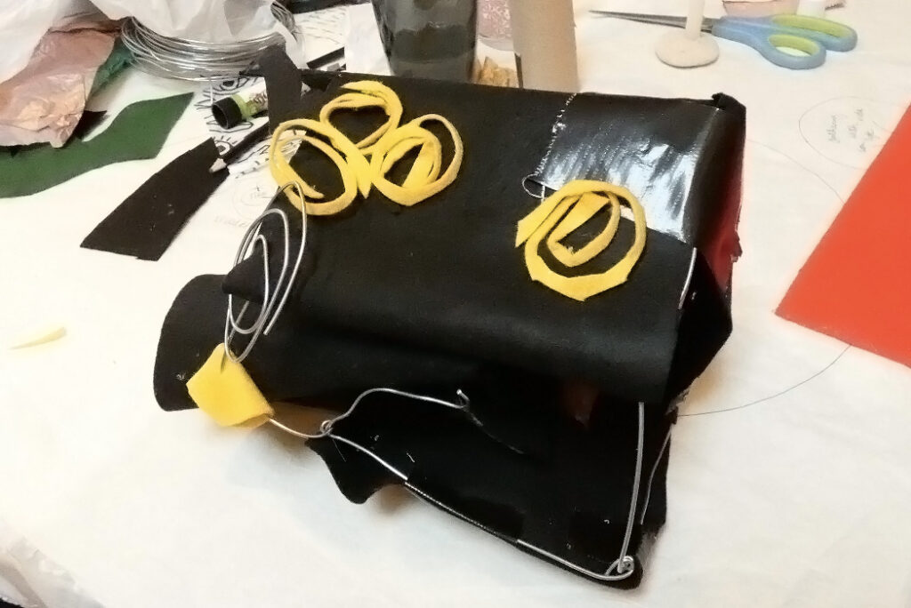 a structure made of black felt and metal with yellow spirals on it
