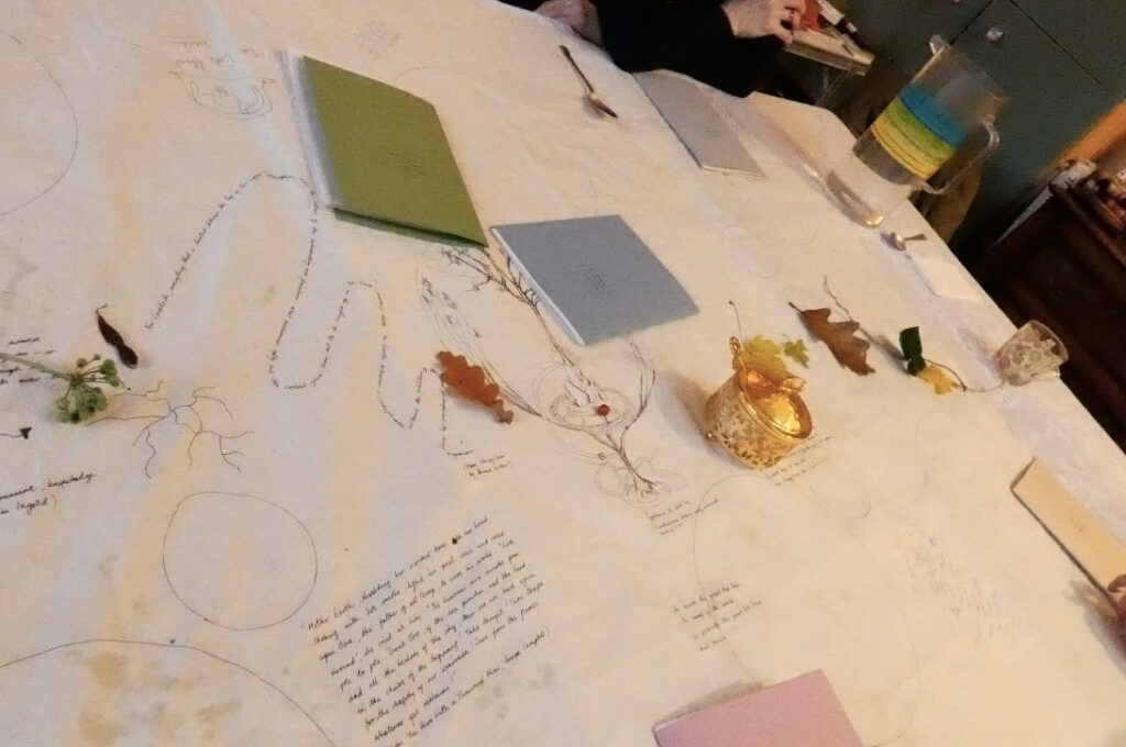 Table set with a tablecloth with drawings and writing on it, notebooks and autumn leaves