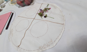an embroidered circular panel with 4 seasons in each quarter of the circle and flowers in the summer quarter