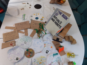 circular drawings on paper place mats, models of shelters and a robotic flood management machine, the Rituals and Robots book and the Convivial Tablecloth